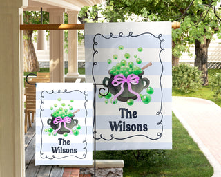 Personalized Halloween garden flag with bubbling green cauldron and pink bow – custom family name outdoor décor