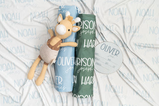 Cozy baby girl swaddle in blush pink with engraved birth announcement plaque for first photos.