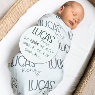 Personalized newborn swaddle blanket with matching wooden birth announcement sign for hospital photos.