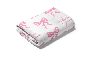Personalized white baby blanket with pink bows and custom name in script font – soft minky nursery bedding