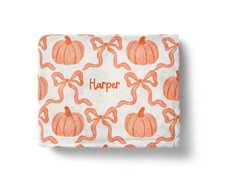 Personalized pumpkin baby blanket with bows in orange and white fall design.