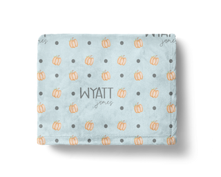 Custom name Halloween blanket with small orange pumpkins and grey polka dots on a soft blue background.