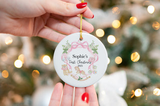 Personalized baby’s first Christmas ornament with pink bow, rocking horse, teddy bear, and custom name for newborn keepsake.