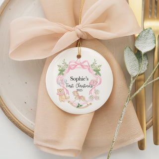 Custom baby’s first Christmas ornament 2025 with pink wreath, teddy bear, rocking horse, and personalized name design.