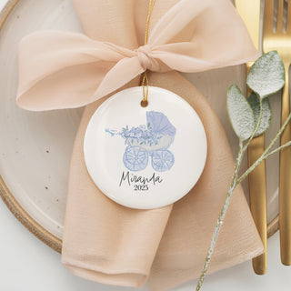 Custom ceramic ornament with watercolor blue baby carriage and flowers, personalized with name “Miranda” and year 2025 — a special baby’s first Christmas keepsake.