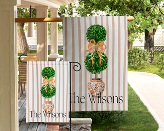 Personalized garden flag featuring a watercolor boxwood topiary with a peach ribbon bow and custom family name.