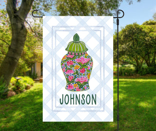 Custom outdoor flag with three green topiary plants in pink ribbon pots and family name