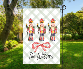 Personalized Christmas garden flag featuring three nutcrackers and a red bow with family name – The Navy Knot holiday décor