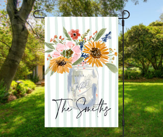Personalized fall garden flag featuring a watercolor mason jar filled with sunflowers and wildflowers on a soft sage striped background with a custom family name.