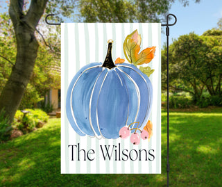 Personalized pumpkin garden flag featuring a large watercolor orange pumpkin with fall leaves and a custom family name on a soft sage striped background.