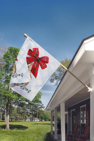 Elegant personalized holiday garden flag with red plaid ribbon and festive bells – custom décor by The Navy Knot