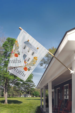 Custom fall garden flag with a watercolor front door, autumn pumpkins, floral planters, and personalized family name for farmhouse porch decor.