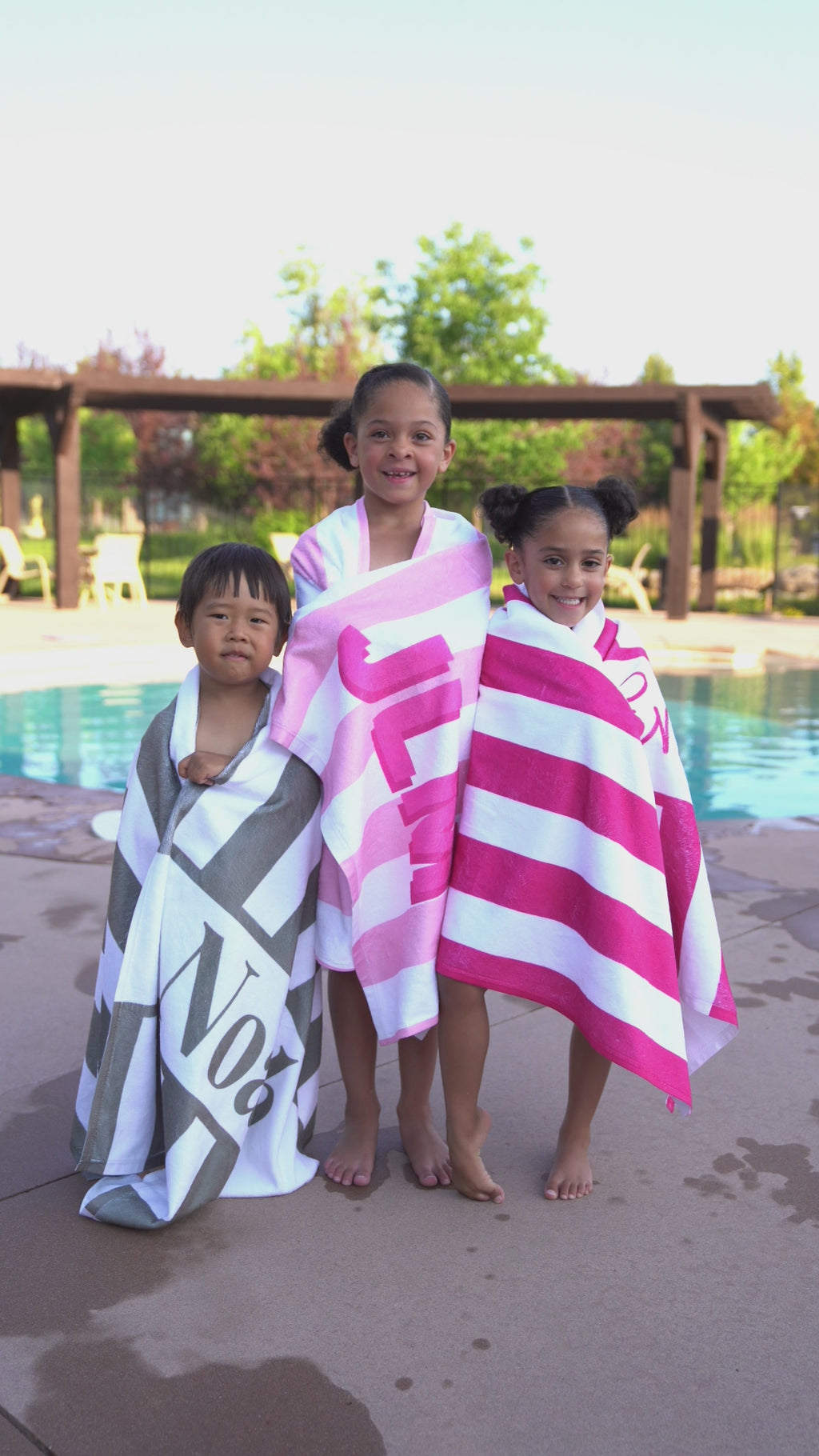 Kids enjoying summer by the pool with monogrammed beach towels – fun and functional personalized swim gear.